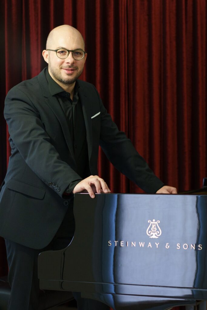 Angelo Morelato accanto al pianoforte a coda Steinway